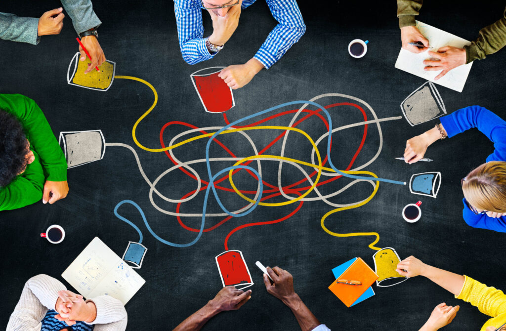 a top-down photo of people sitting at a table having a discussion with a tangle of lines connecting different people