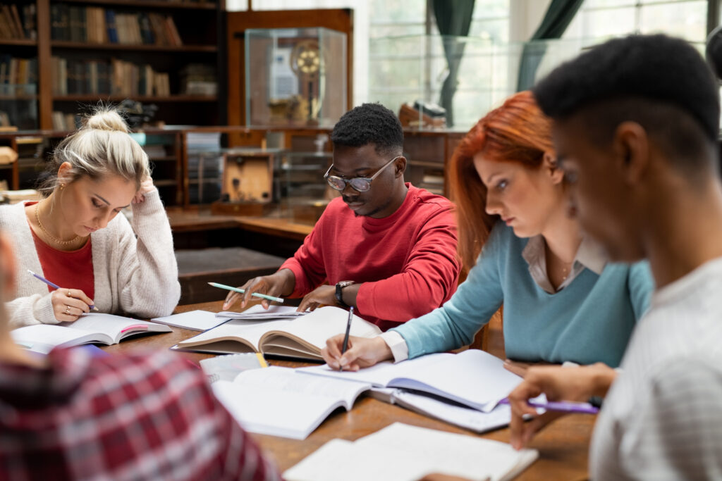 a group of students working at a table in a library looking very serious and not making eye contact with each other