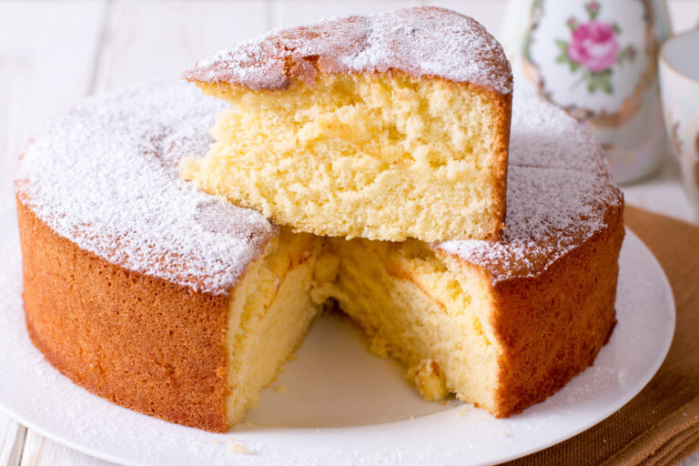 a white cake with one slice removed and placed on top of the rest of the cake