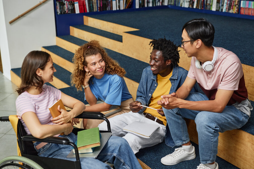 Diverse group of young people discussing work in college library